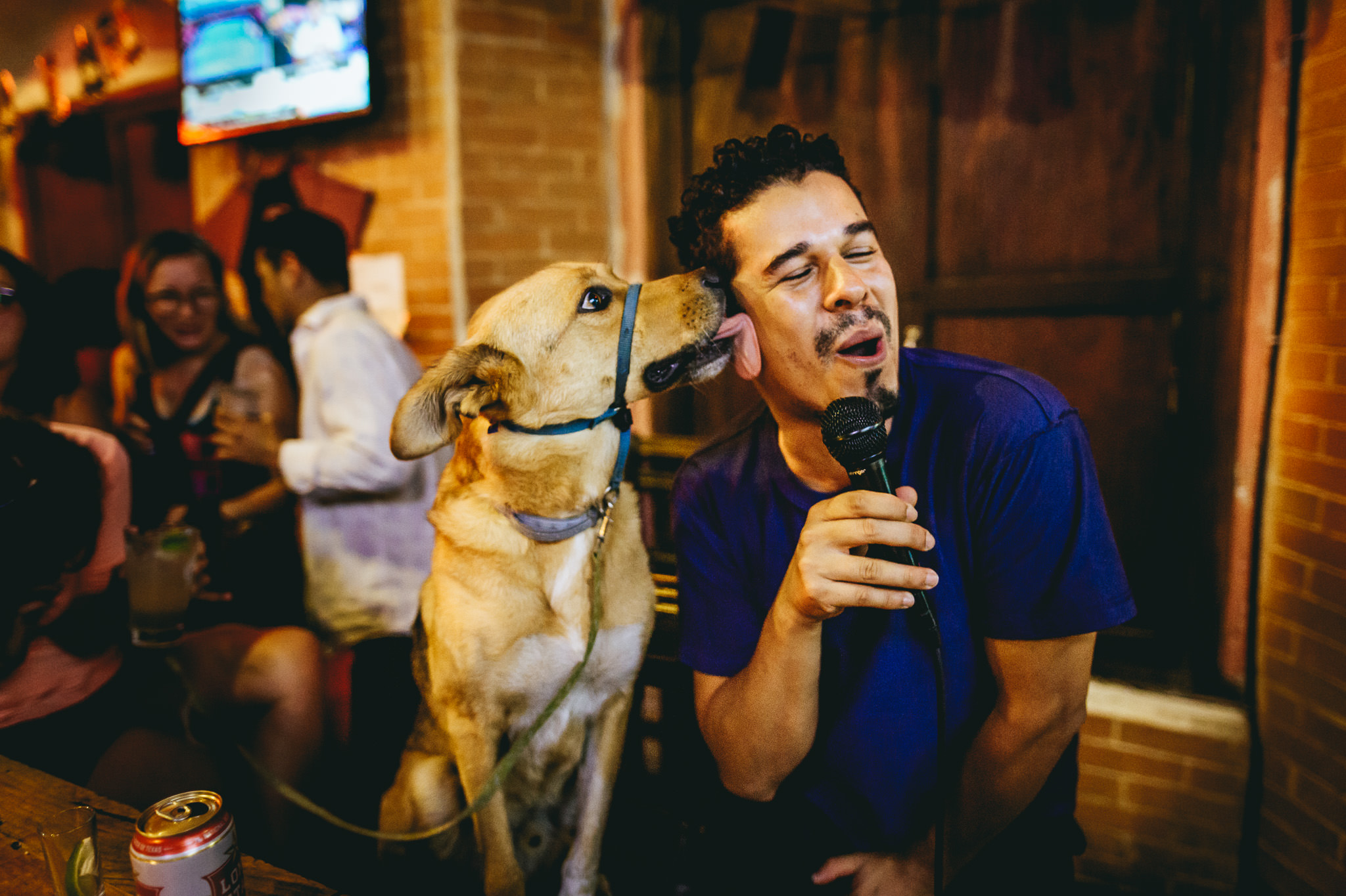 Tender moment between dog and his owner as the friendly dog licks the face of a singer during karaoke night | Bullseye Pub | Antigua Guatemala