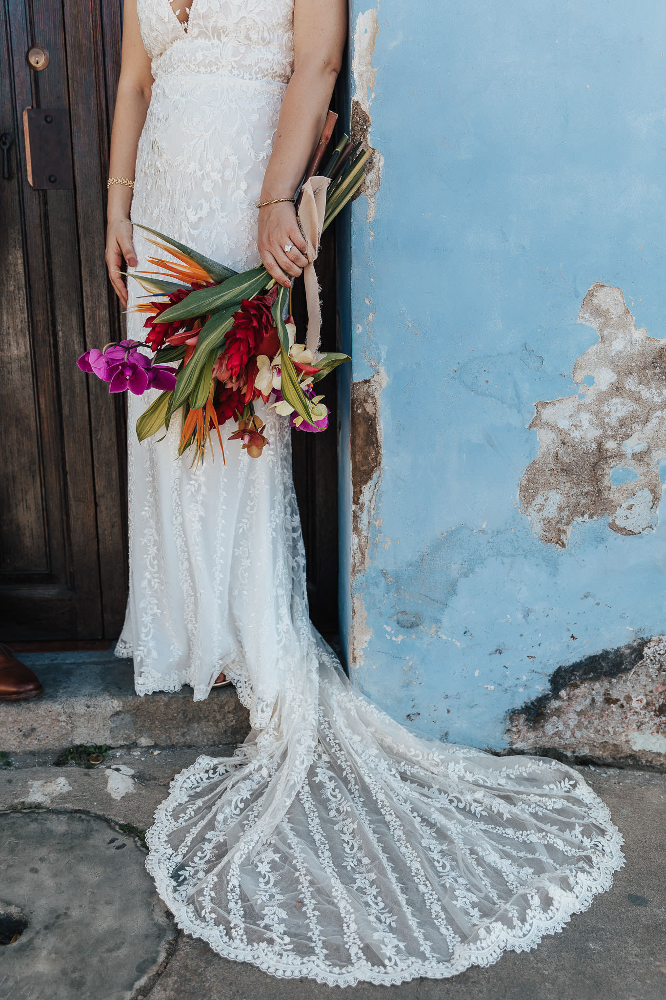 Stylish bride in stunning wedding dress and colorful, tropical bouguet
