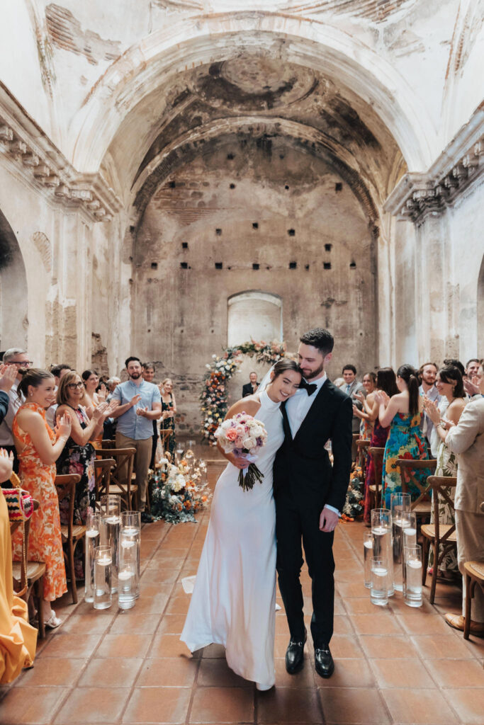 Newlyweds walking out of the church ruins — joyful moment from a romantic destination wedding in Antigua Guatemala